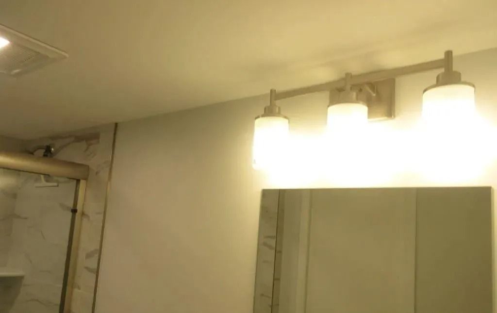 Bathroom mirror and bright vanity lights above a sink.