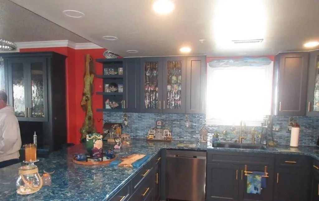 Kitchen with dark cabinets, blue tile backsplash, and a bright window above the sink