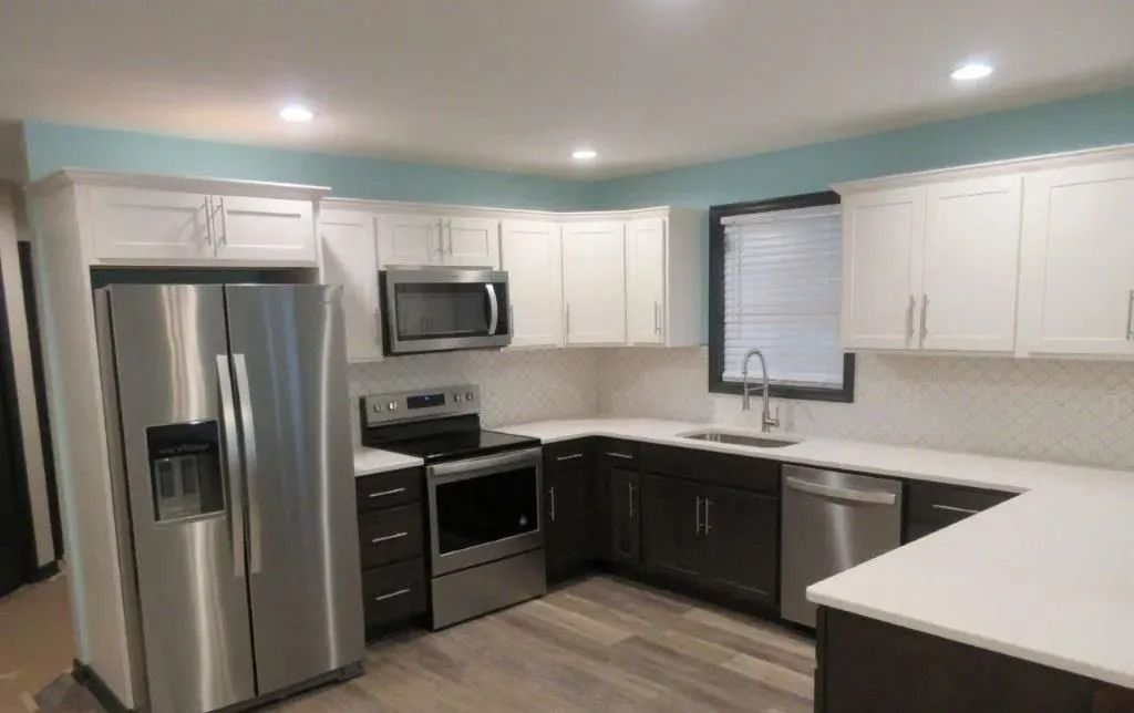 Modern kitchen with stainless steel appliances, white cabinets, dark lower cabinets, and a breakfast bar