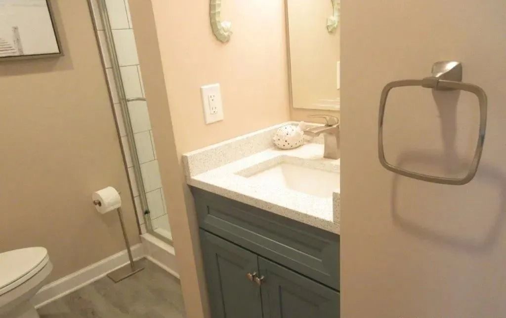 Bathroom with toilet, shower stall, and vanity sink beside a towel ring on the door.