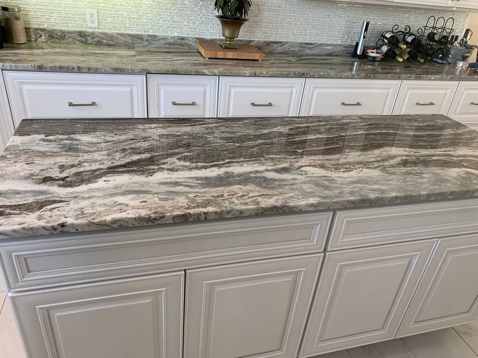 Kitchen island with a gray-and-white marbled countertop and white cabinets in a modern kitchen