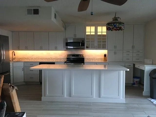 Bright white kitchen with a large island, built-in cabinets, and warm under-cabinet lighting