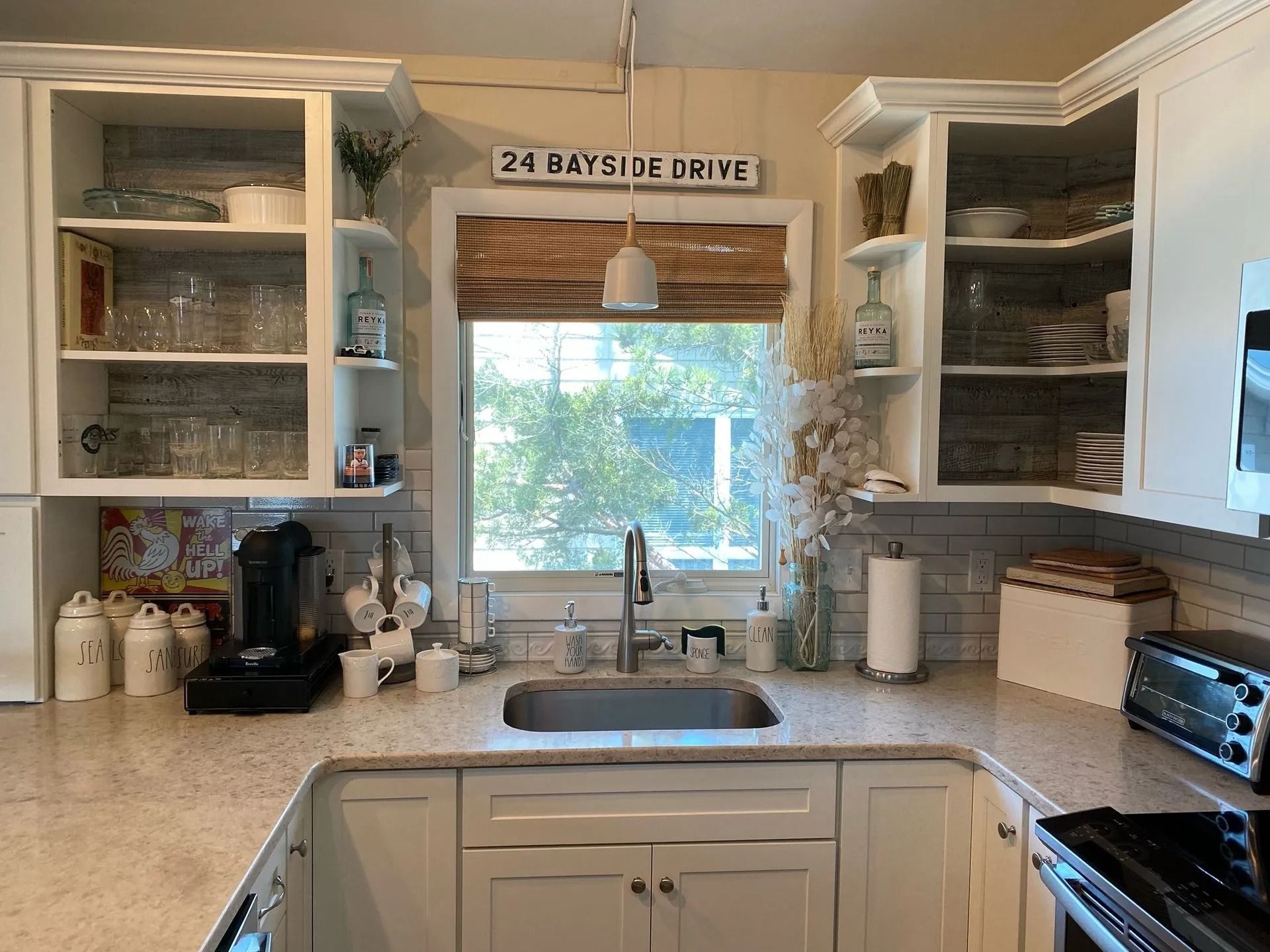 Bright kitchen with white cabinets, granite counters, sink by window, and coffee maker on the left.