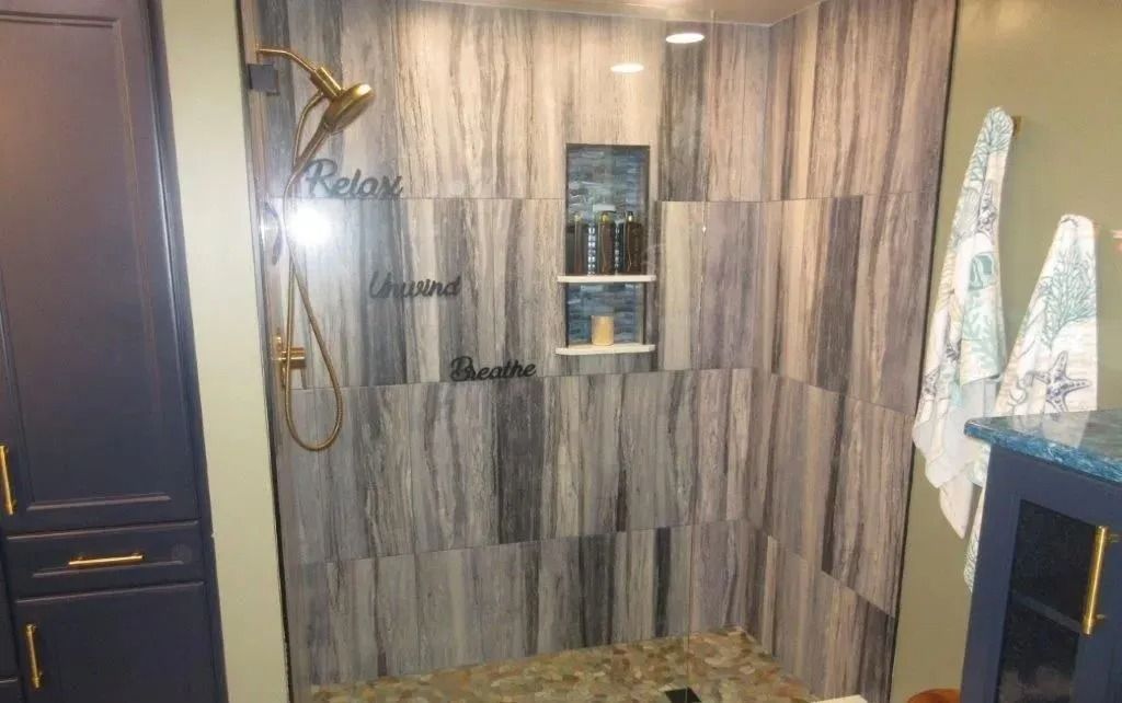 Modern shower with wood-look tile walls, brass fixtures, and a small recessed niche.