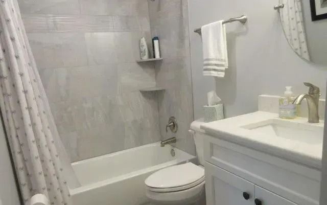 Bright white bathroom with tub-shower, toilet, vanity sink, and towel rack