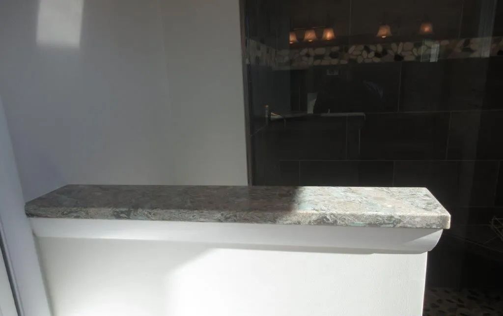 White kitchen island with speckled granite countertop in a dimly lit room