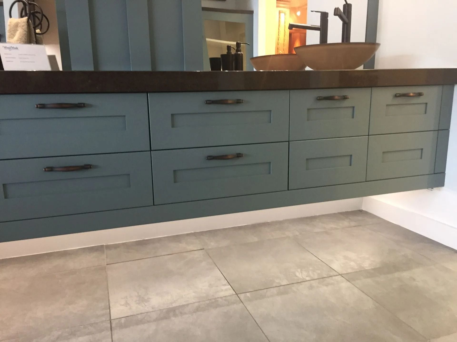 Dark green kitchen island with drawers and a dark countertop on a light tiled floor