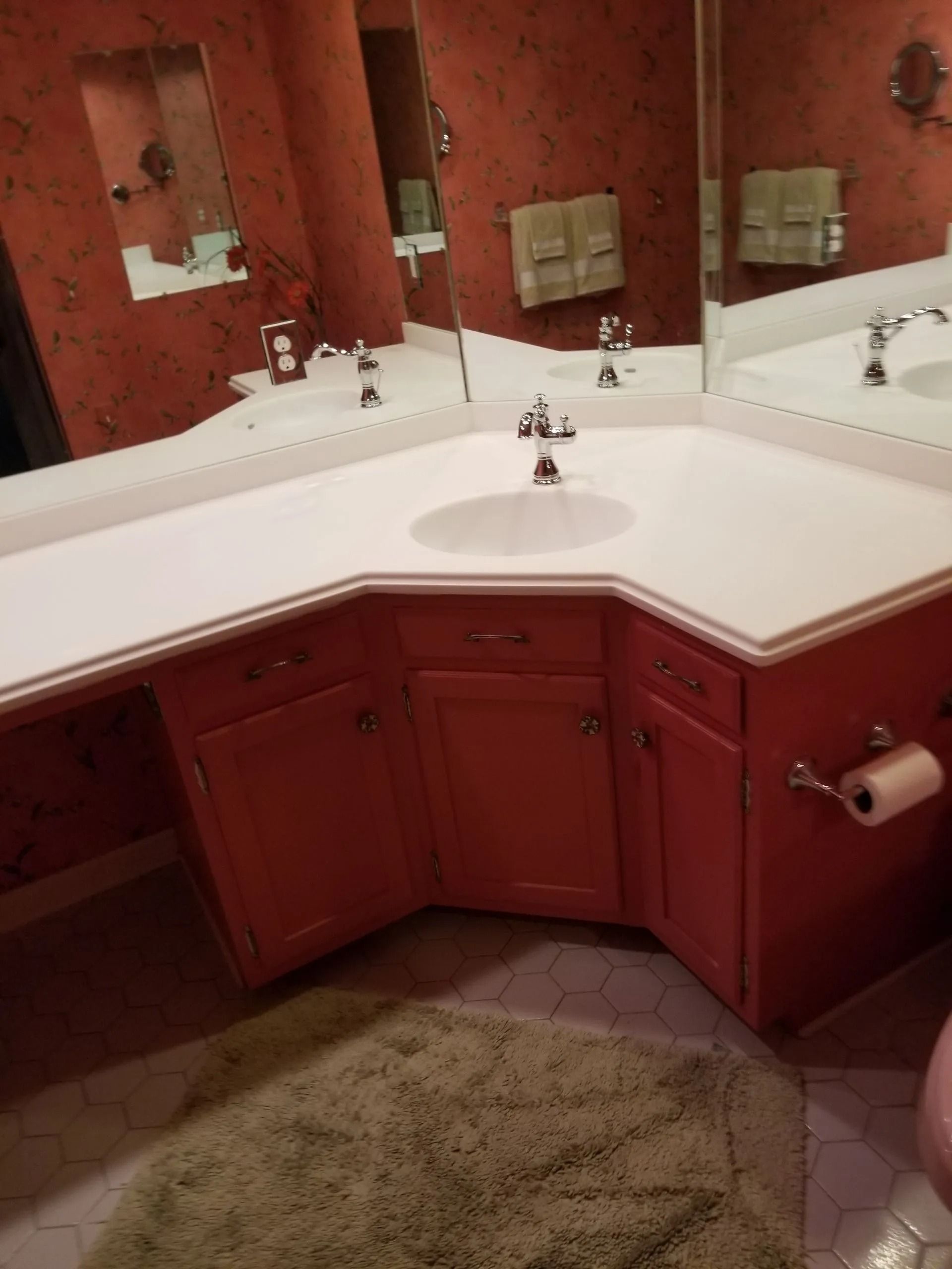 Red bathroom vanity with white countertop, sink, mirror, and beige carpet.