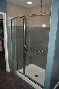 Glass shower stall with chrome frame, sliding door, and white shower base in a bathroom