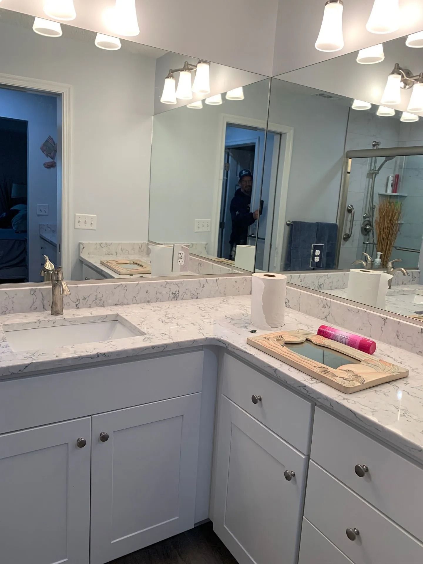 Bright bathroom with white double vanity, marble countertop, mirrors, and pendant lights