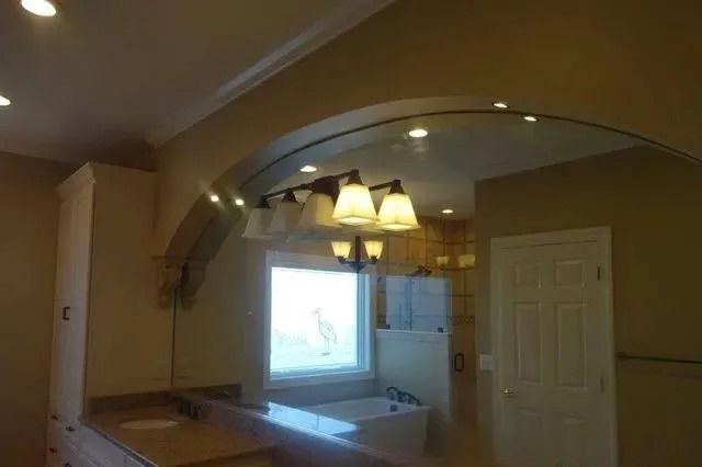 Kitchen with arched pass-through, hanging lights, and window above the sink