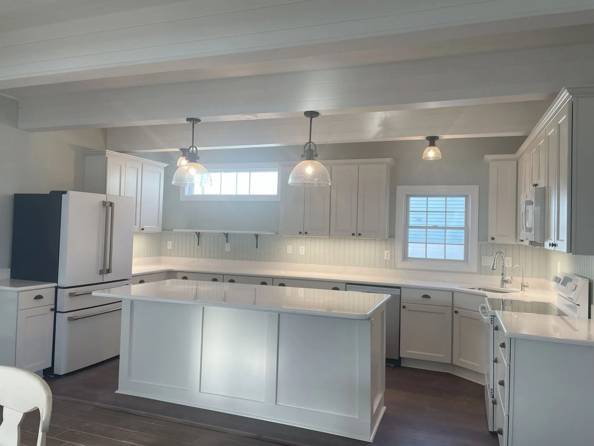 Bright white kitchen with central island, pendant lights, and built-in cabinets