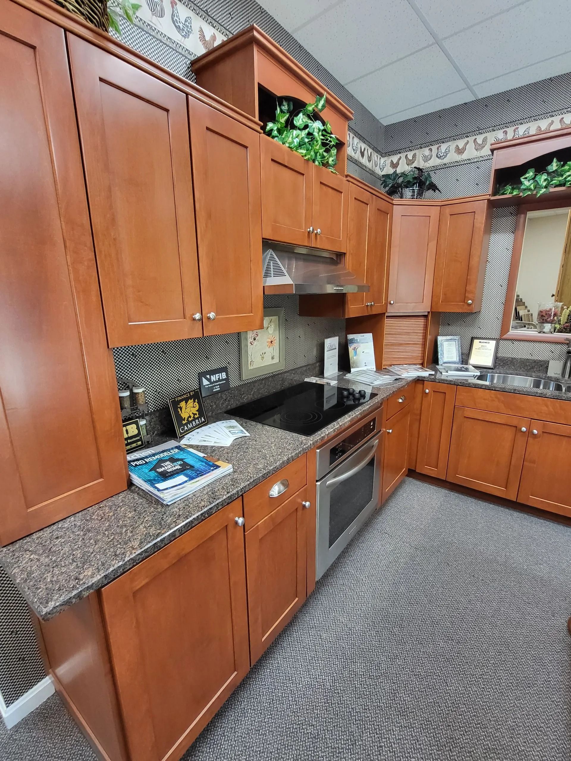 Kitchen with wood cabinets, granite countertops, stainless stove, and patterned tile flooring.