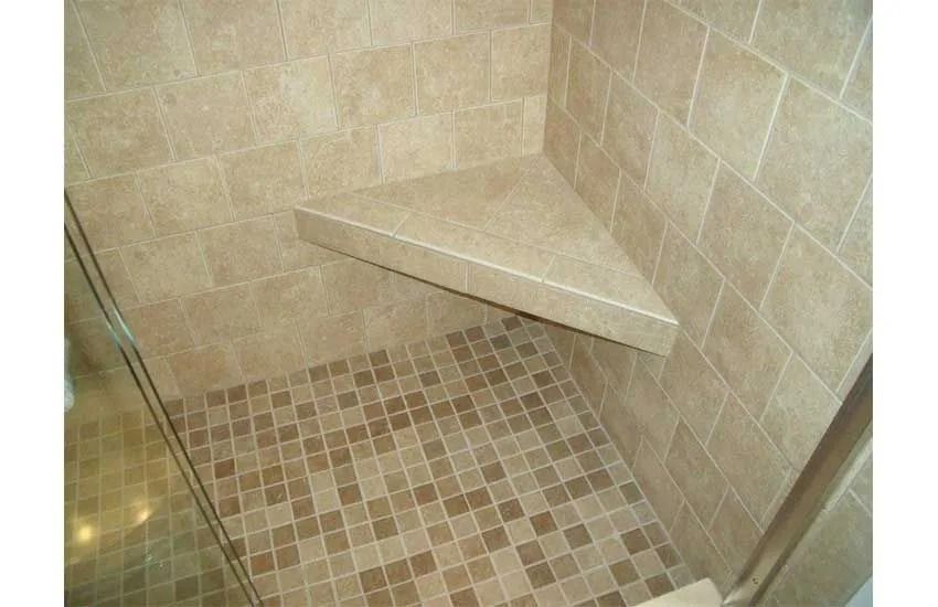 Tiled walk-in shower with a built-in corner bench and mosaic floor drain area