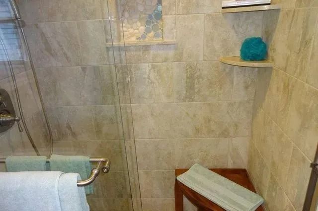 Bathroom with glass shower, teal towel, and tiled walls, seen from above
