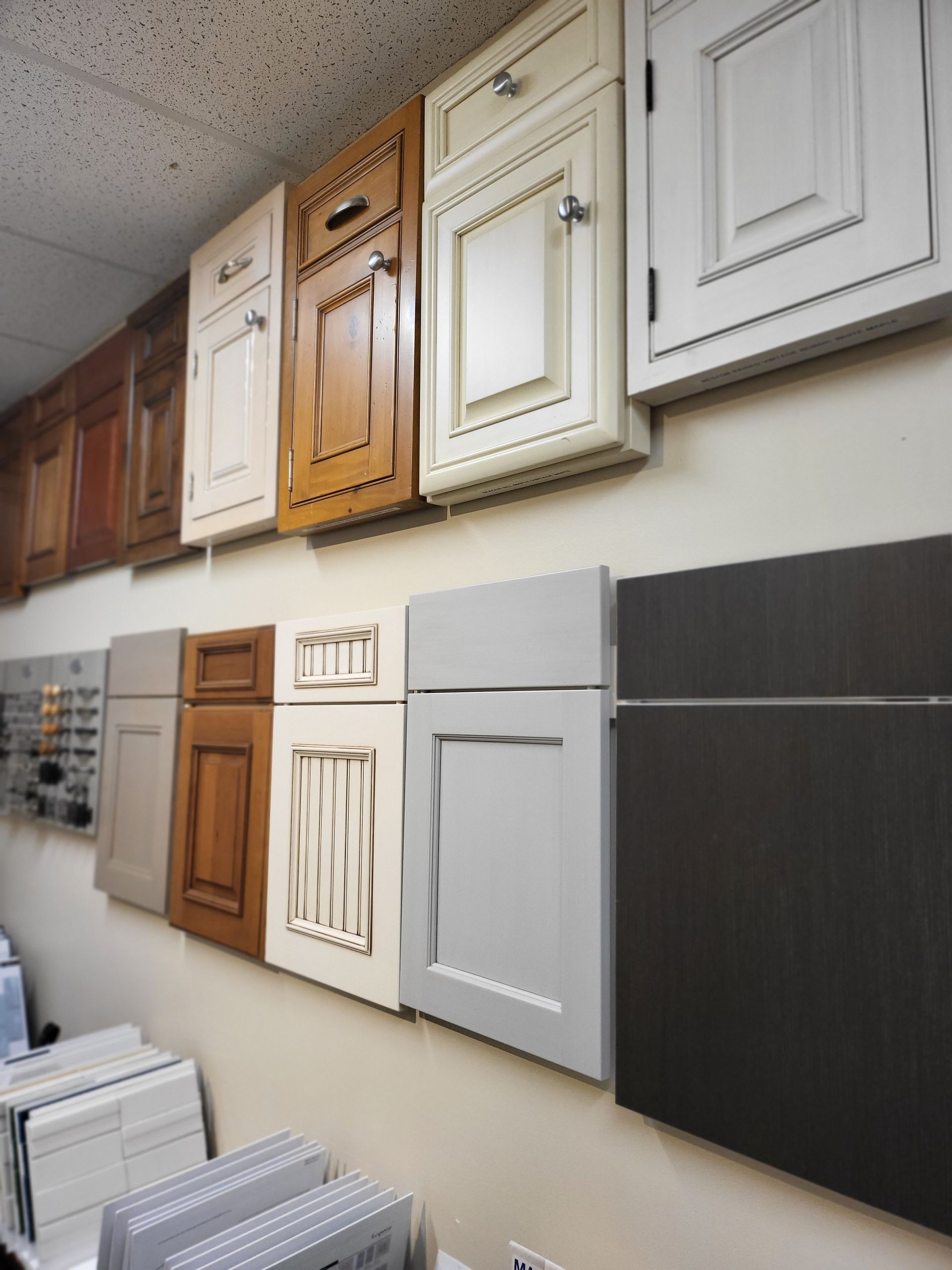 Display of assorted cabinet door samples in a showroom, arranged in rows on a wall.