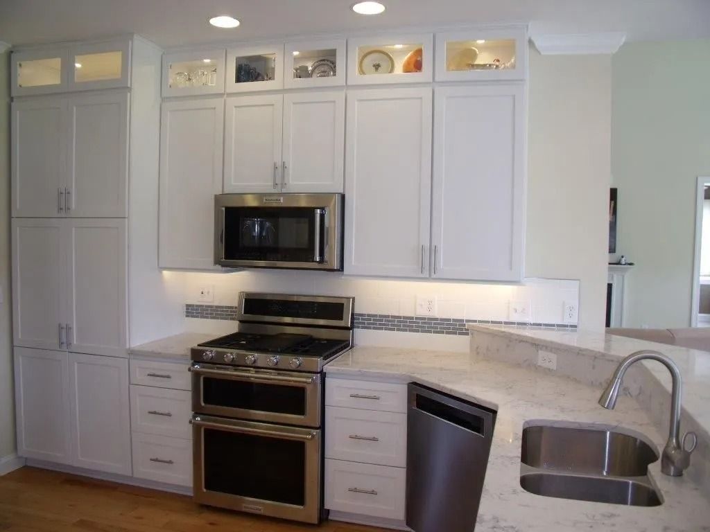 Modern white kitchen with stainless steel appliances, white cabinets, and granite counters