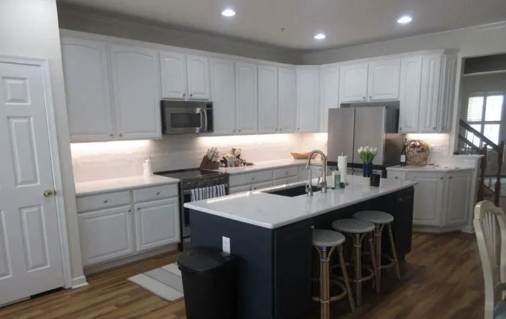 Bright modern white kitchen with island, bar stools, and stainless steel appliances