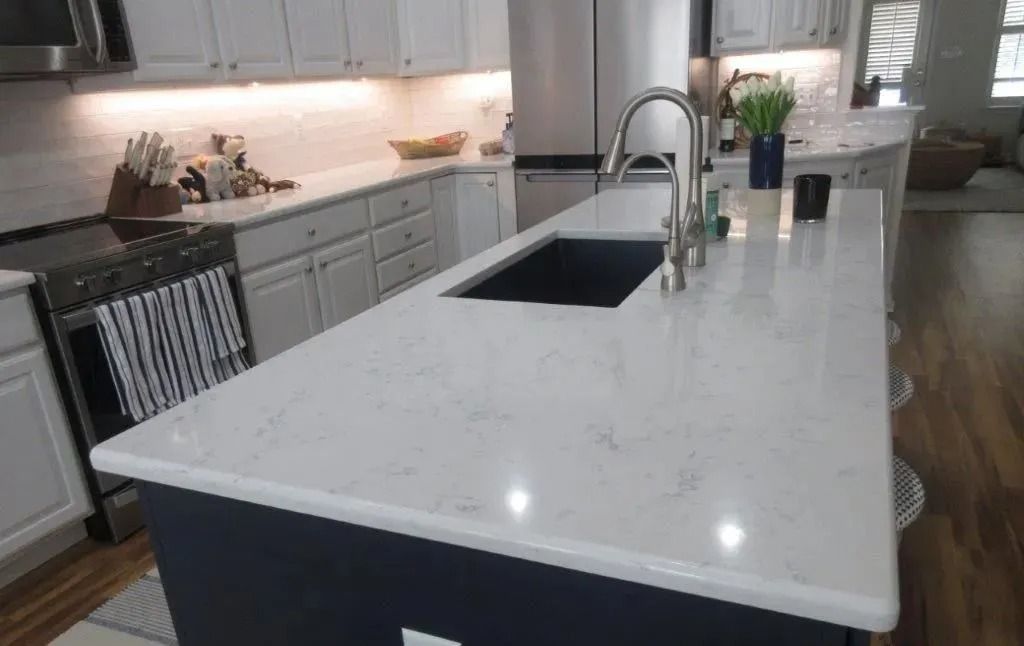 Modern white kitchen with large marble island, built-in sink, and wood floors