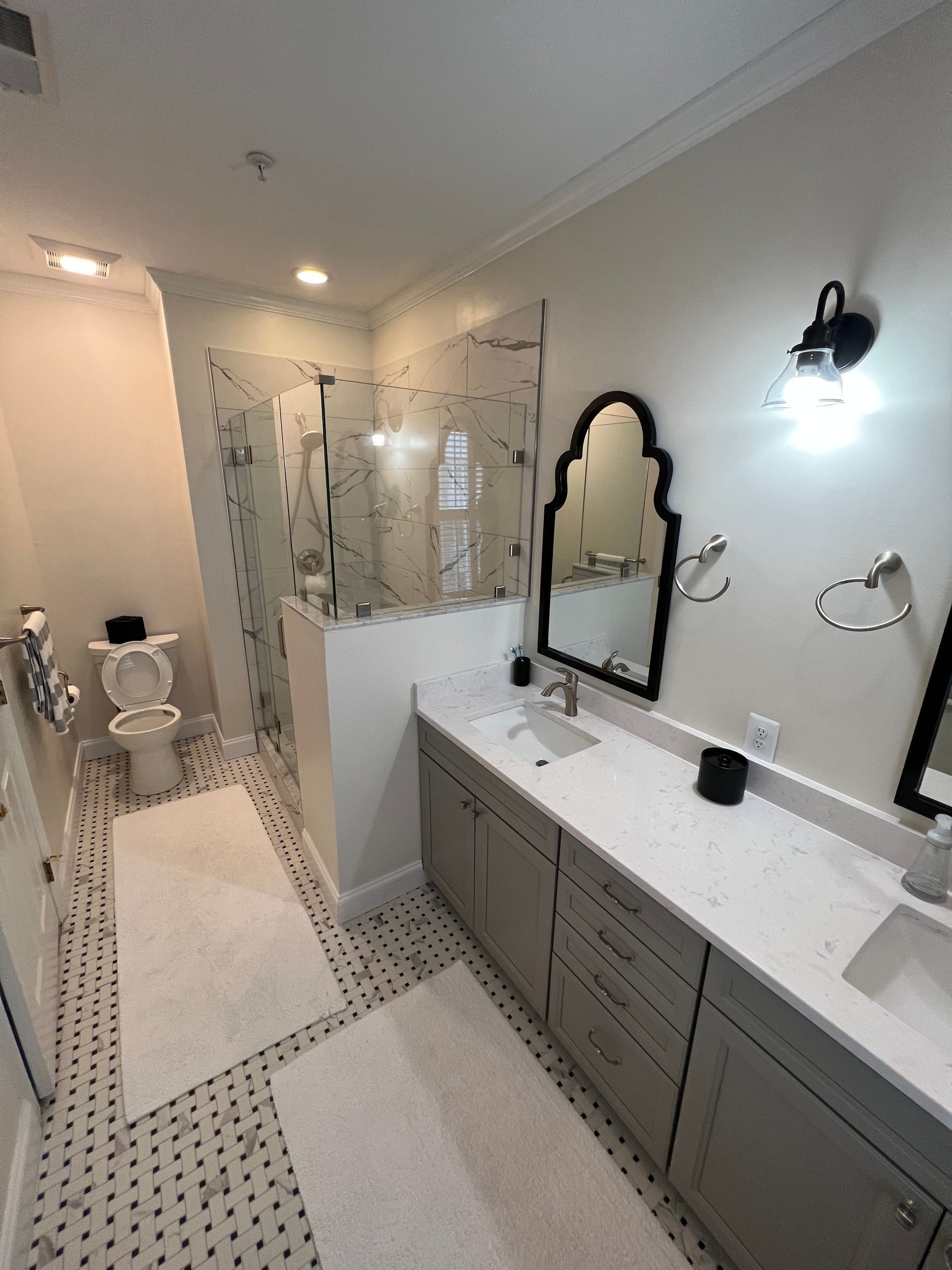 Bright bathroom with double vanity, large mirror, and walk-in shower with glass doors.