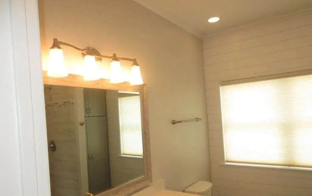 Bathroom with vanity lights, mirror, and window with blinds