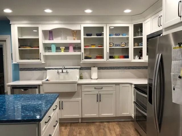 Modern kitchen with blue island, white cabinets, stainless steel appliances, and open shelving