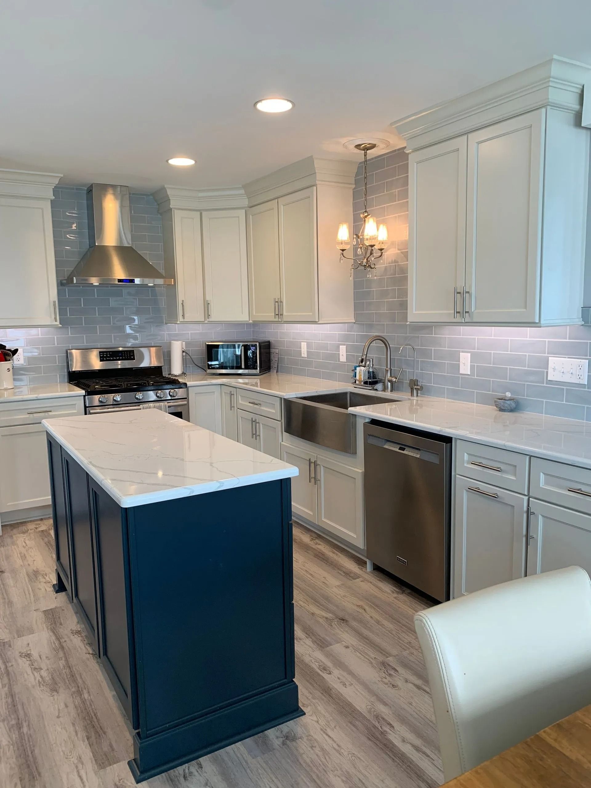 Bright modern kitchen with white cabinets, stainless steel appliances, and a navy island