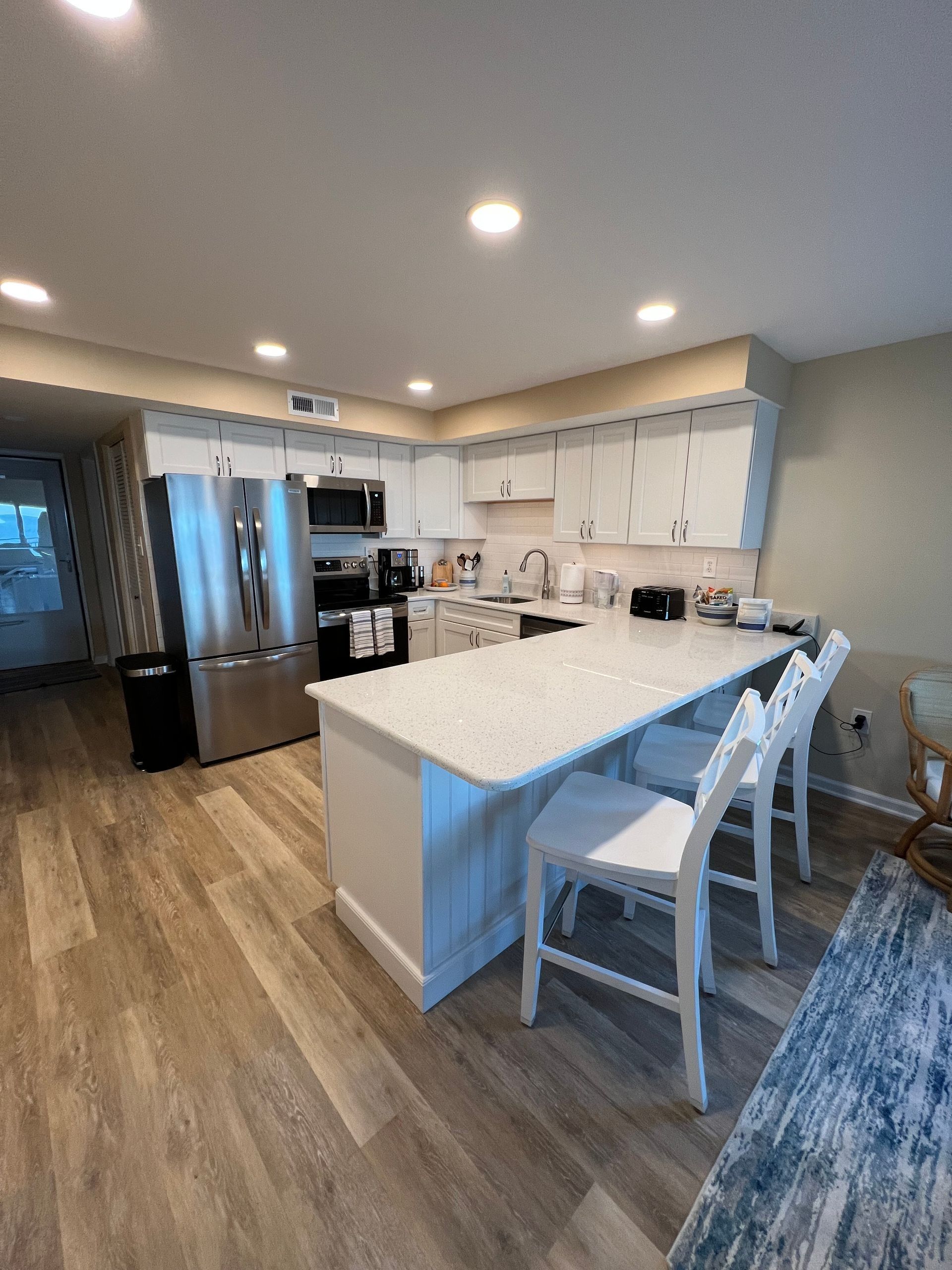 Modern kitchen with white cabinets, large island, stainless appliances, and wood floors