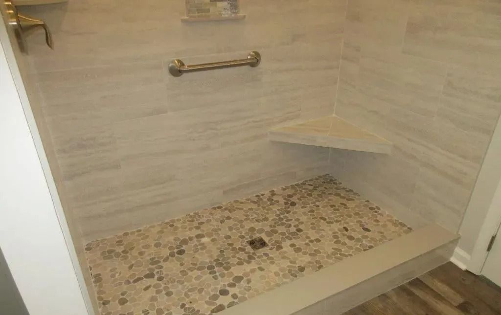 Walk-in shower with bench, grab bar, and mosaic tile floor in beige stone tones