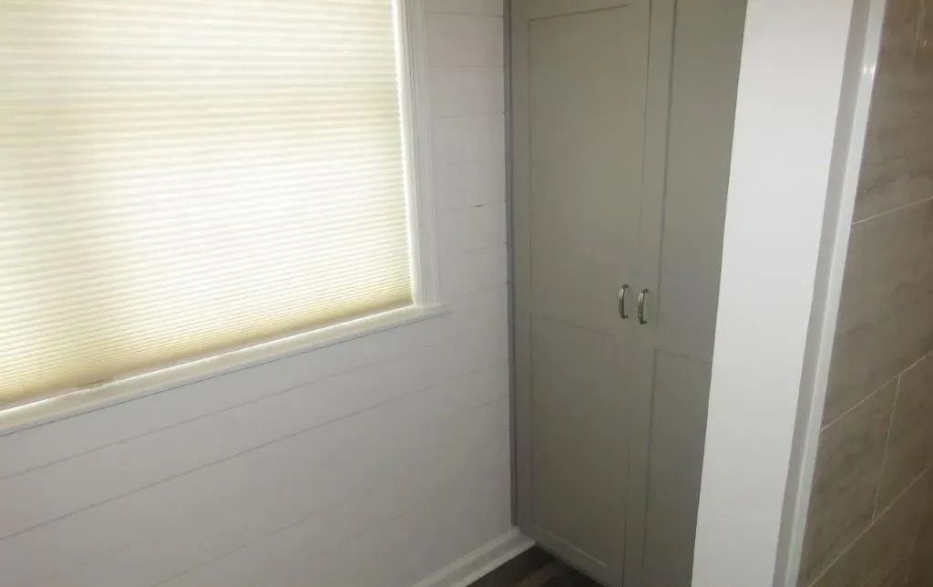 Small room corner with a window blind and a tall gray storage cabinet.