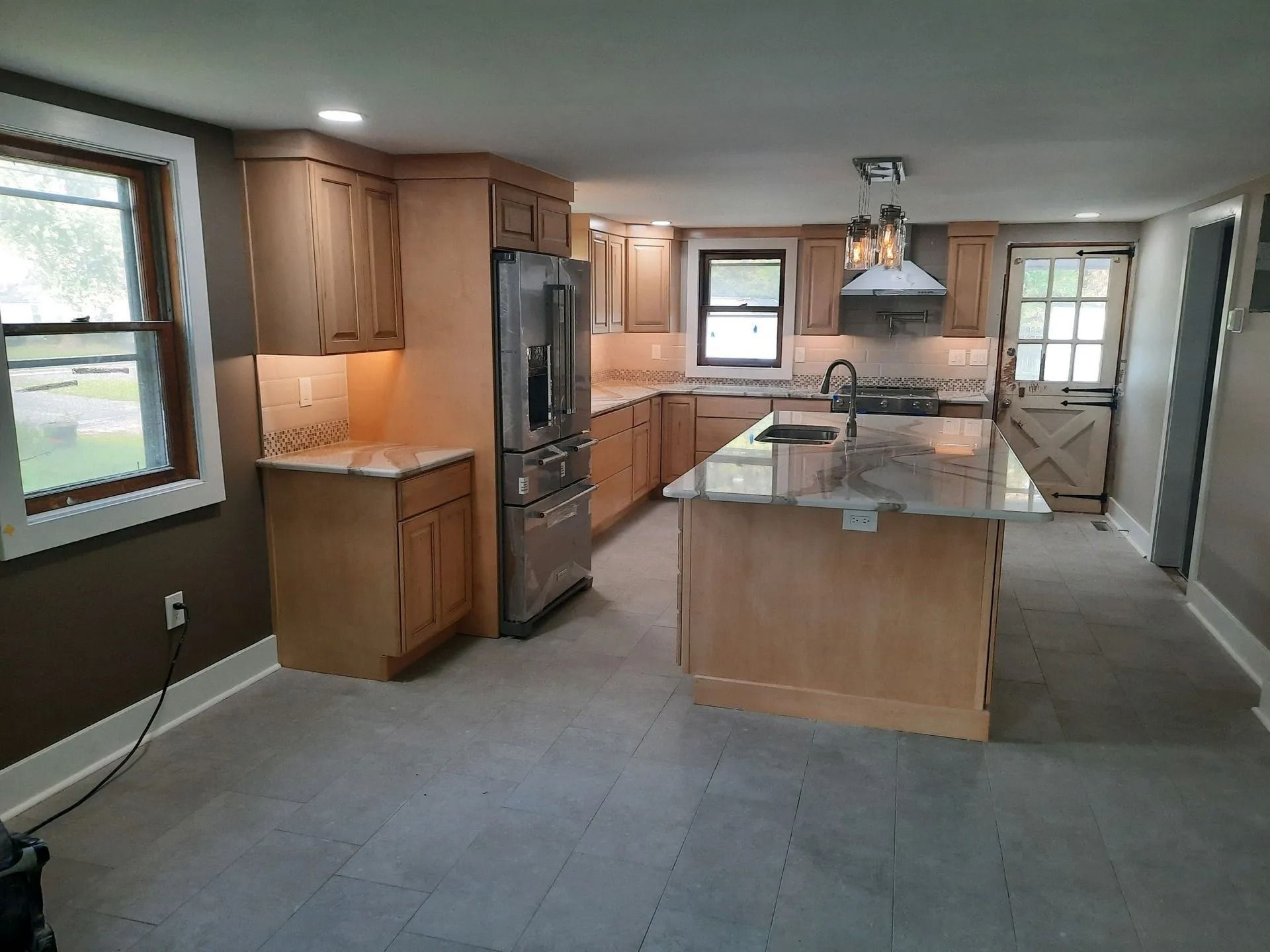 Spacious modern kitchen with wood cabinets, central island, and large windows.