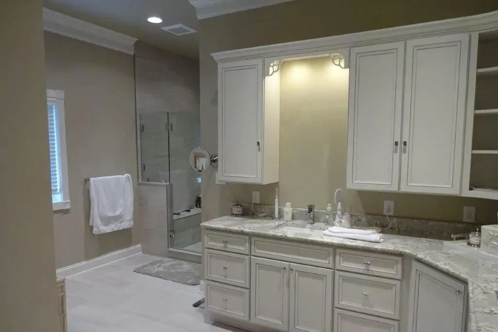 Modern bathroom with double vanity, large mirror, and glass-enclosed shower, in beige and white tones