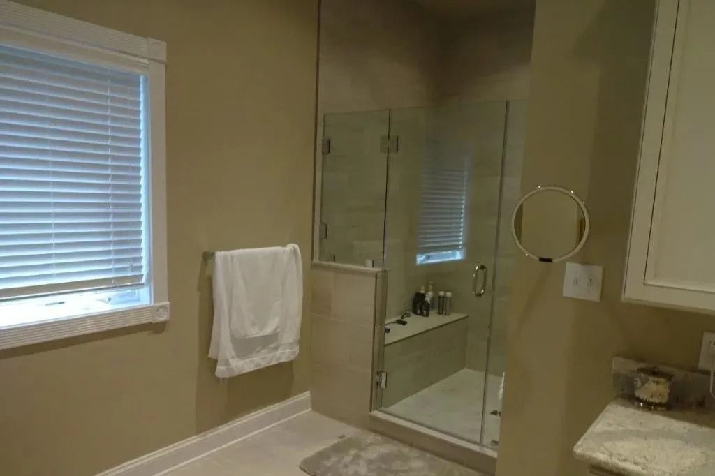 Bathroom with bathtub, glass shower door, window blinds, towel rack, and vanity sink.