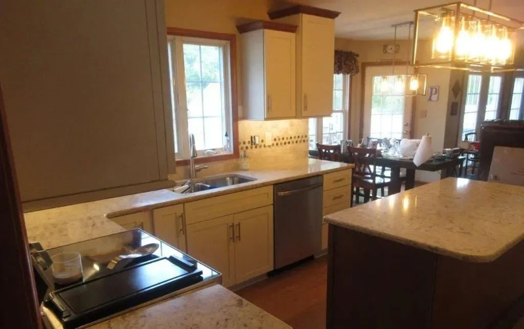 Modern kitchen with tan cabinets, granite island, and dining area in the background
