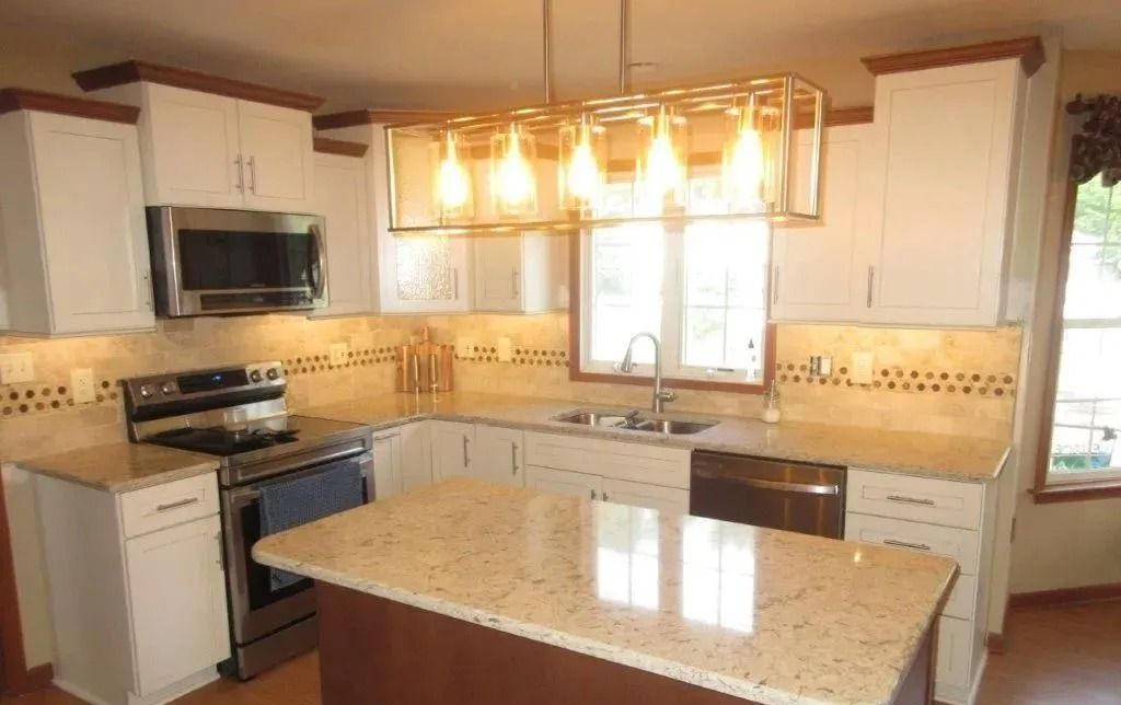 Bright modern kitchen with white cabinets, granite island, stainless appliances, and pendant lights over a windowed sink
