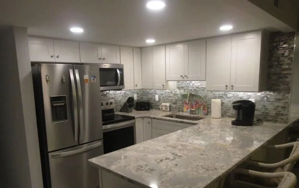 Modern kitchen with stainless steel appliances, granite island, and recessed ceiling lights