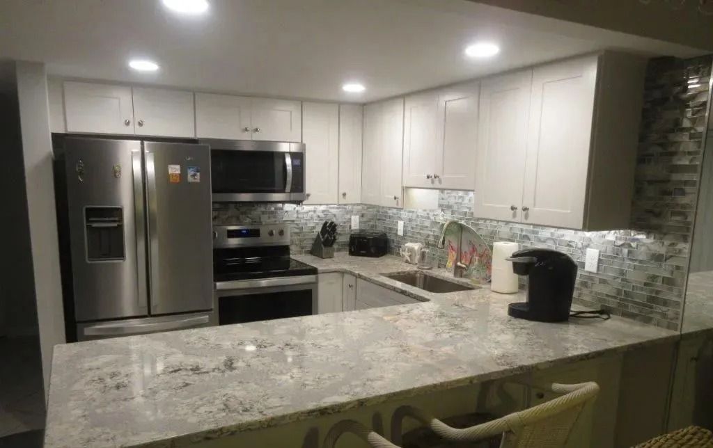 Modern kitchen with stainless steel appliances, white cabinets, granite countertops, and recessed lighting