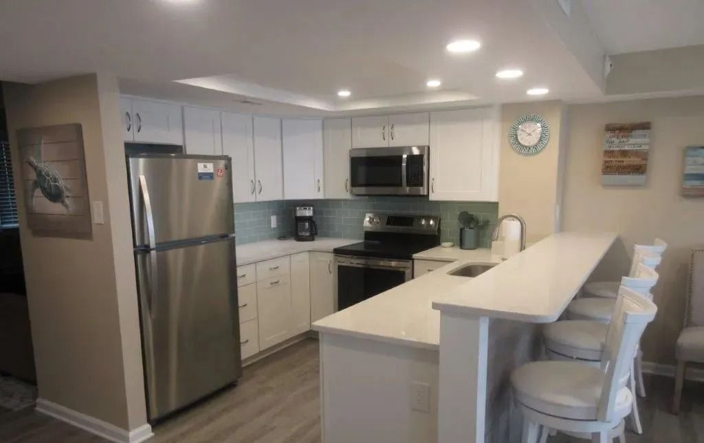 Modern kitchen with stainless steel appliances, white cabinets, and a breakfast bar with stools