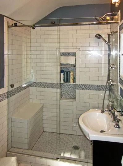 Tiled walk-in shower with glass door, built-in shelf, and a sink on the right side.