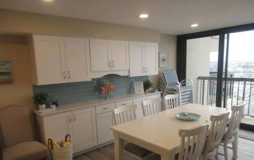 Bright kitchen-dining area with white cabinets, table, chairs, and sliding glass doors to a balcony.