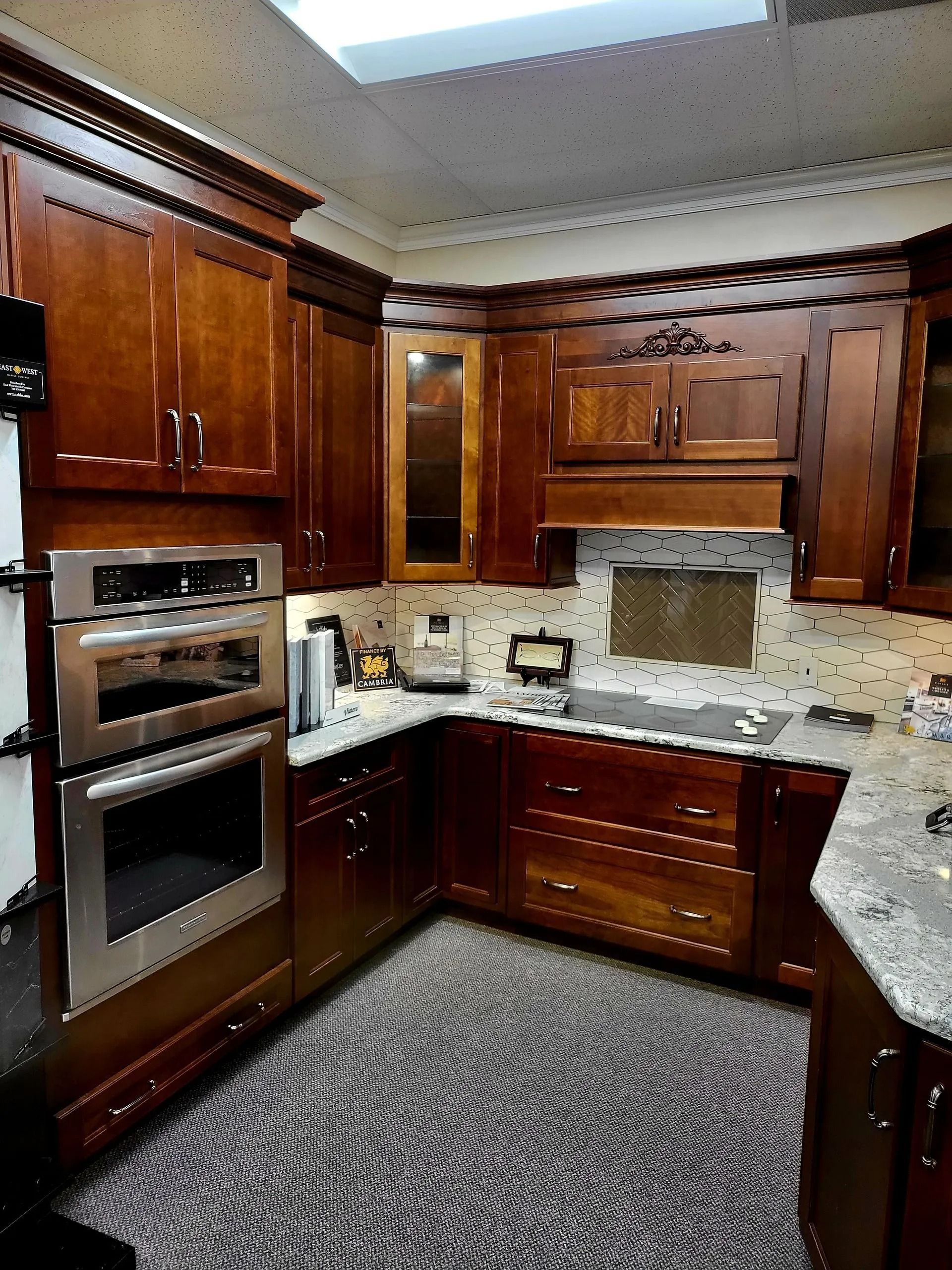 Wooden kitchen with dark cabinets, built-in oven, granite counters, and patterned rug.