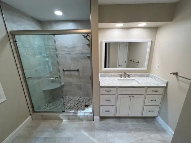 Bathroom with glass shower, vanity, mirror, and beige walls and tile flooring