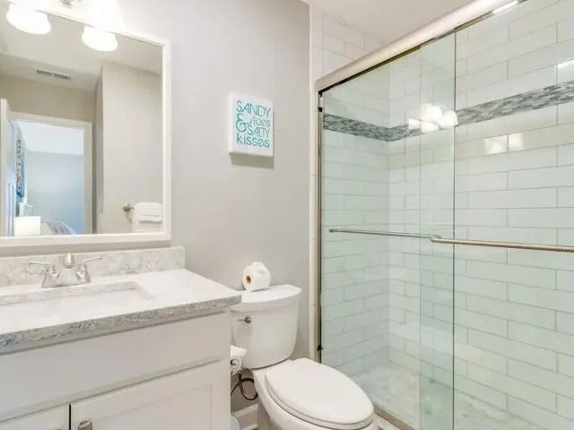 Small white bathroom with vanity, toilet, and glass shower enclosure