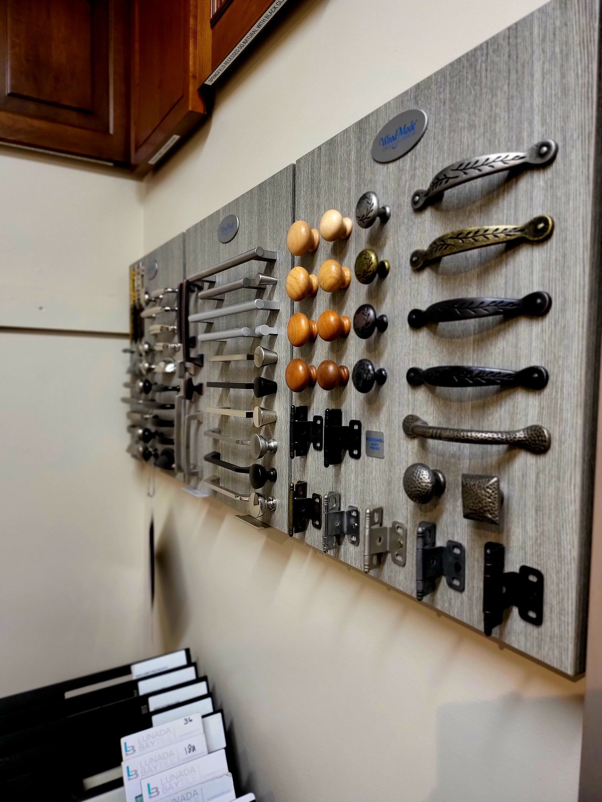 Assorted cabinet handles and knobs displayed on a wall-mounted board in a showroom.