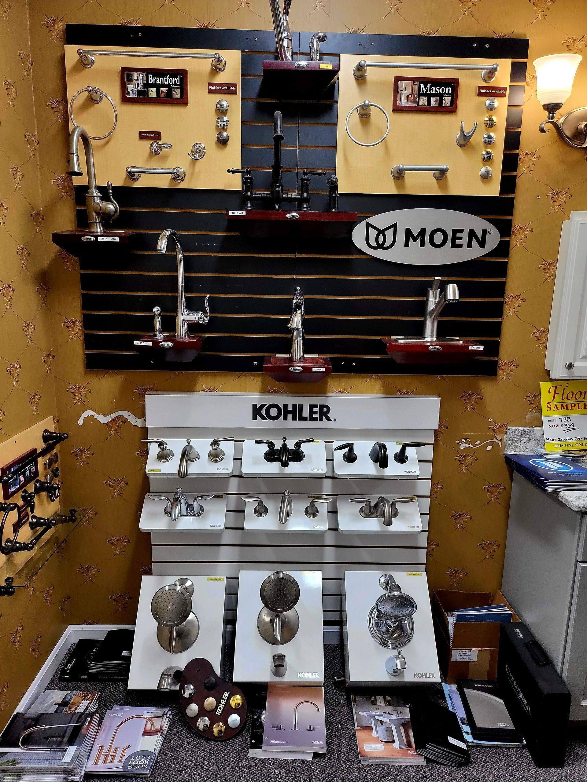 Display wall of Moen and Kohler kitchen and bath faucets on gold and white panels