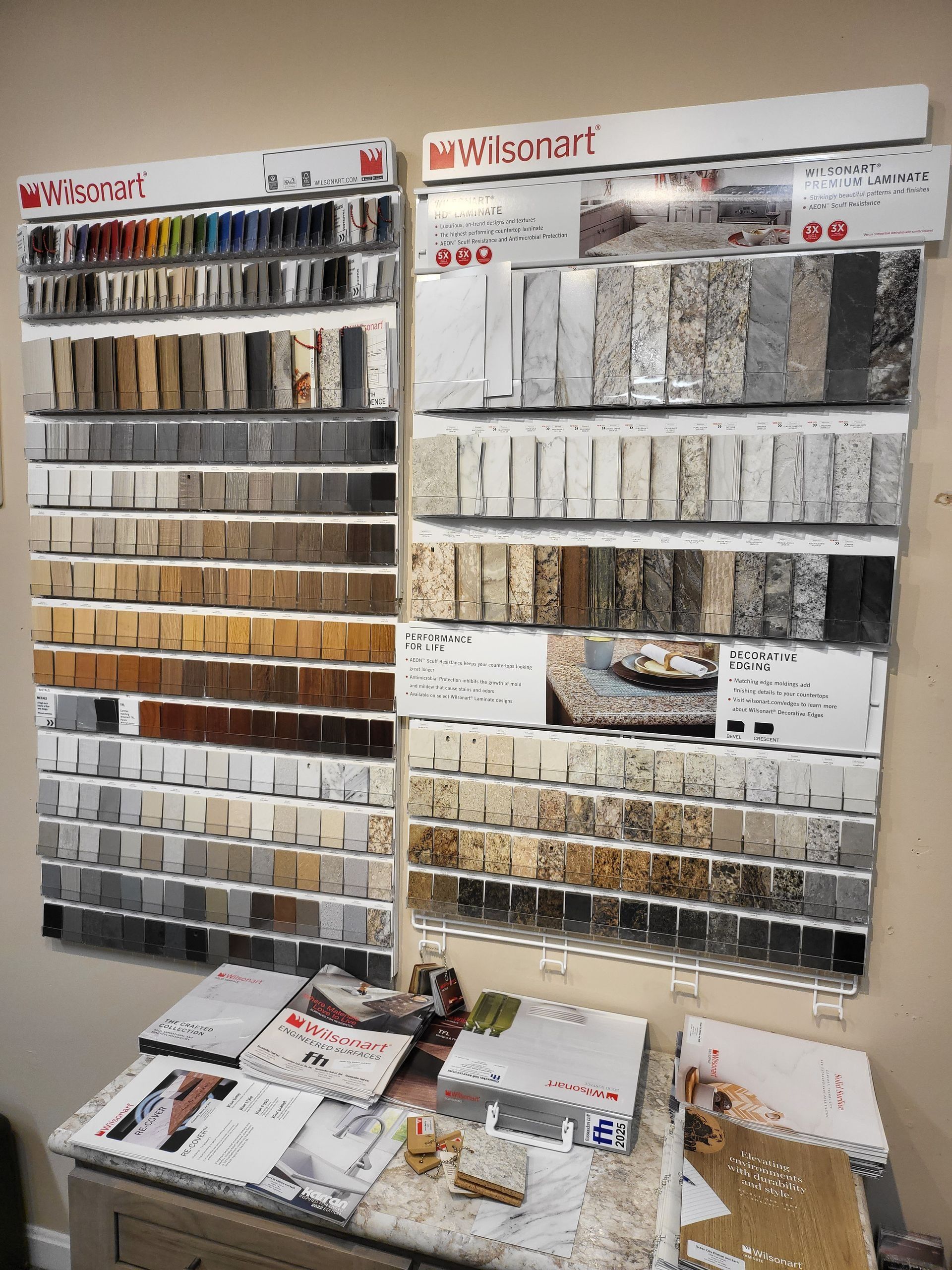 Interior design showroom wall displaying fabric, wallpaper, and material samples on organized racks and tables.
