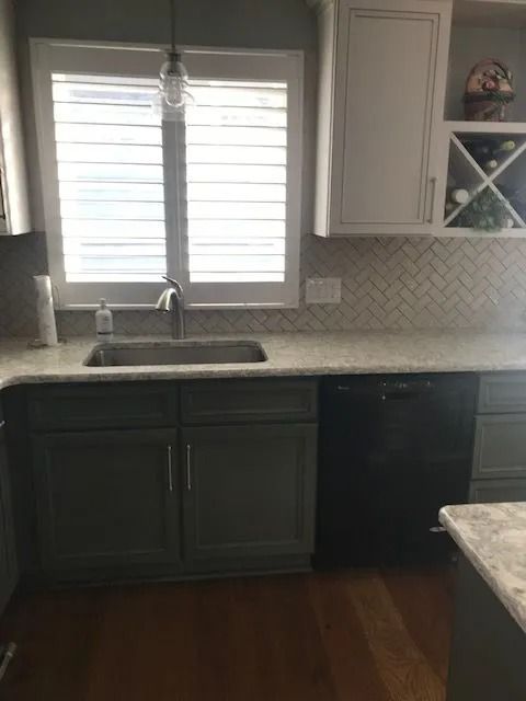 Kitchen sink and window with white shutters, dark cabinets, and granite countertops.