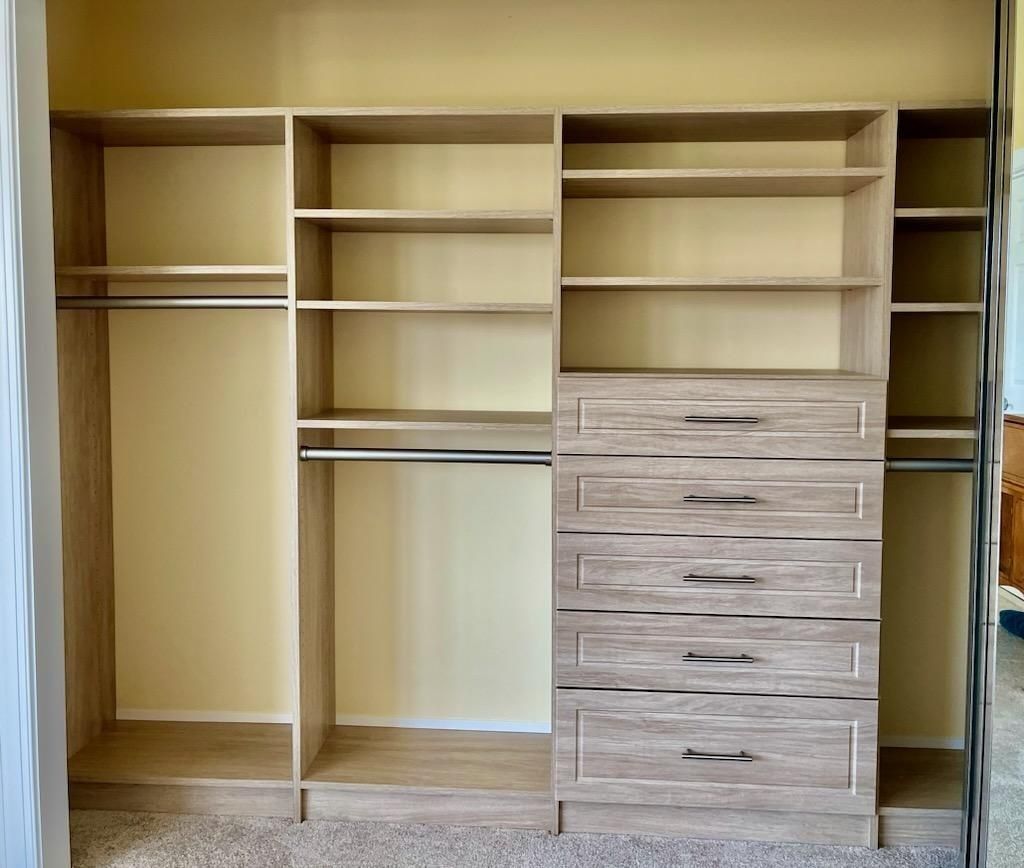 Built-in wooden closet with open shelves and drawers, unfinished in a bedroom.