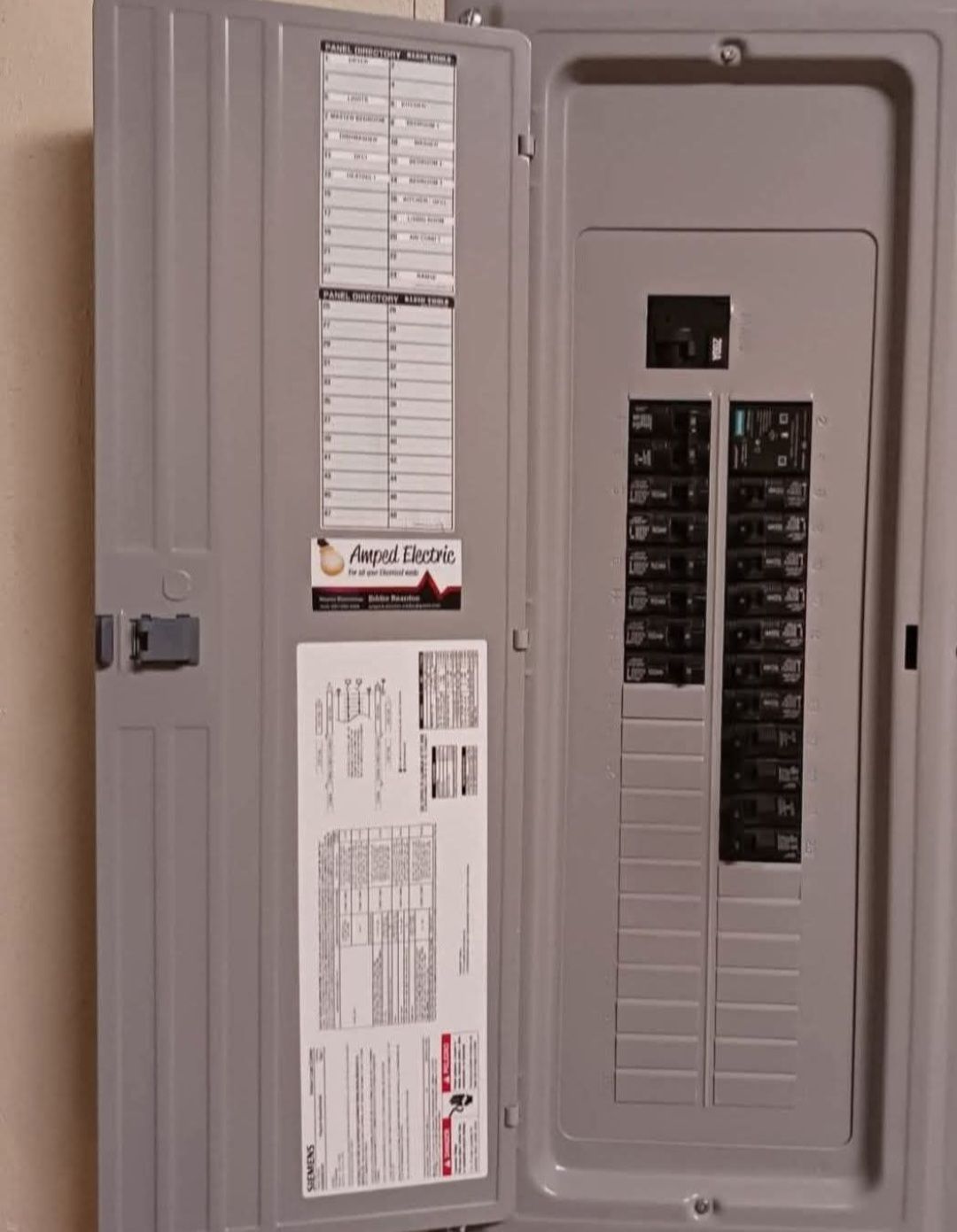 Open electrical breaker panel with door open, showing circuit labels and switches.