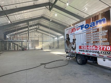 Large empty warehouse interior with a Rev Foam service truck parked on the right.